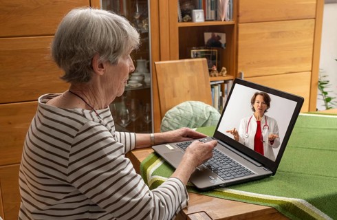 Symbolic image of telemedicine, patient speaking to a doctor in a video conference from home