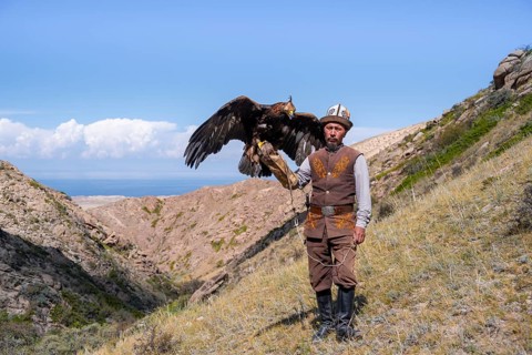 Traditional Kyrgyz eagle hunter with eagle in the mountains, near Kysyl-Suu, Kyrgyzstan, Asia