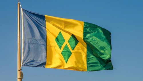 The flag of the Grenadines flutters in the wind, isolated against a blue sky