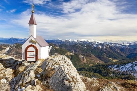 Whitewashed miniature chapel on the Hochgern summit in the Chiemgau Alps under partly cloudy skies