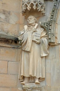 Sculpture and monument of Martin Luther with Bible, Holy Scripture, book at the portal of St