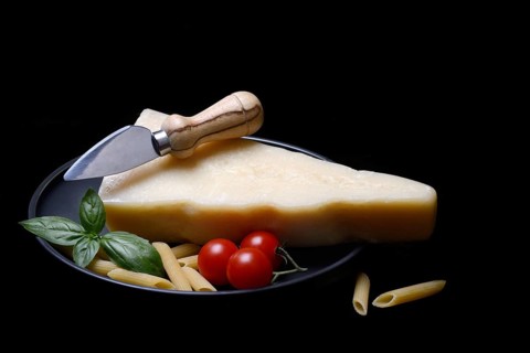 A piece of Parmesan cheese with cheese knife, pasta and tomatoes, Italy, Europe