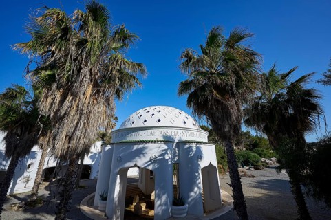 White building with domed roof and palm trees, shown under a clear blue sky, thermal springs,