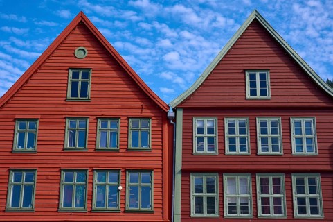 Traditional red wooden houses under a blue sky with pitched roofs and multiple windows in a sunny