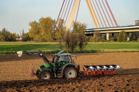 Farmer ploughing a field, tractor with plough, near Neuss, Fleher motorway bridge, A46, North