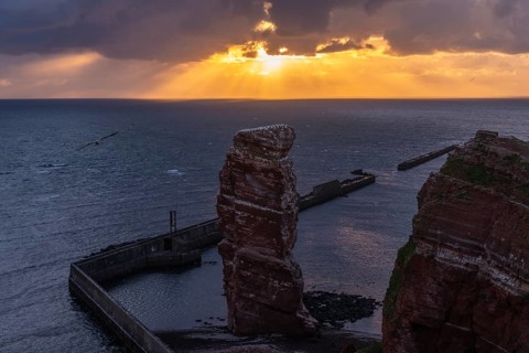 Red sandstone cliff with Lange Anna on the offshore island of Heligoland, mole as protection