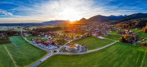 Aerial view of a village in an expansive landscape at sunset, surrounded by mountains, Bad