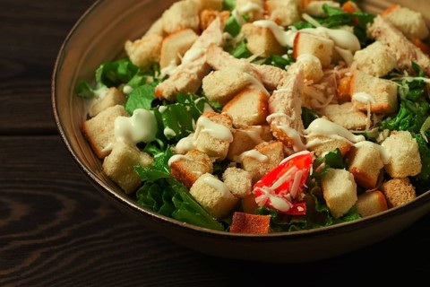 Fresh traditional Caesar salad, with chicken, on a wooden background, Top view, toned, horizontal
