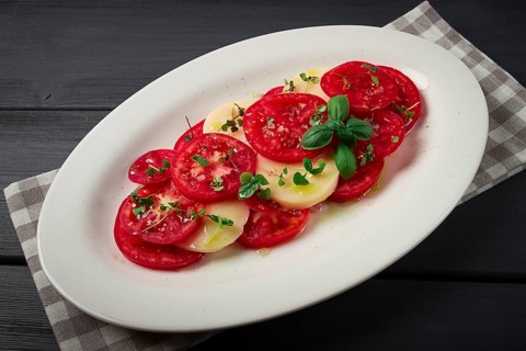 Caprese salad, Italian traditional dish, tomatoes with mozzarella cheese, basil and spices, top
