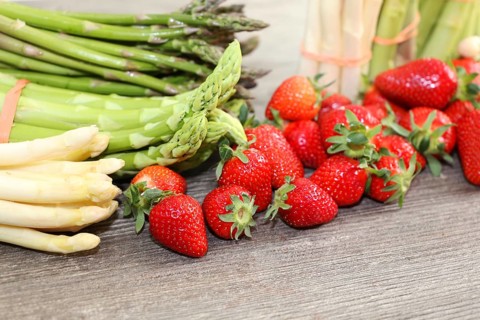 Green asparagus, white asparagus and fresh strawberries decorated on a rustic wooden table