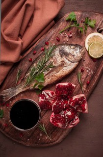 Fried dorado fish, with spices and herbs, on a wooden board, pomegranate sauce, close-up, no people