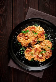 Steak, cauliflower, with cheese, spices, homemade, on a wooden table, dark background, close-up,