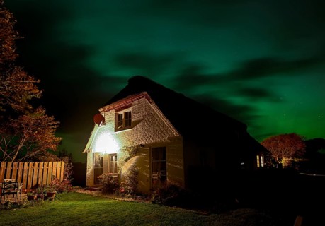 Northern Lights (Aurora borrealis) over a thatched roof house, Junkersmitteldeich, Pellworm Island,