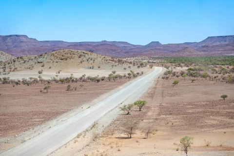 Gravel track leads through barren dry landscape with hills, Damaraland, Kunene, Namibia, Africa