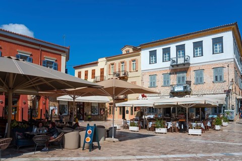 Lively street café with large parasols and colourful buildings under a blue sky, Syntagma Square,