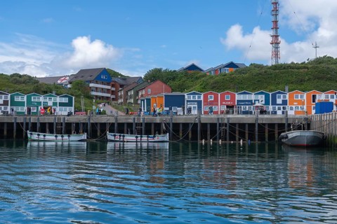 Colourful lobster shacks on the harbour promenade, Börteboote, offshore island Helgoland, blue sky,