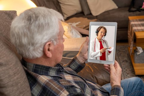 Symbolic image of telemedicine, elderly patient speaking to a doctor in a video conference from