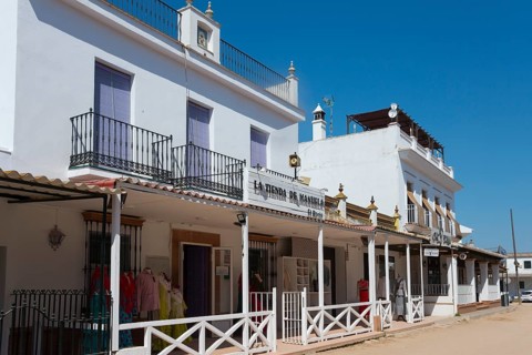 Eine sonnige Straßenszene mit weißen Gebäuden und Geschäftsfassaden im spanischen Stil unter blauem