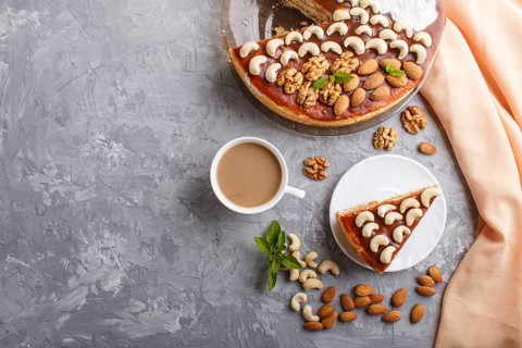 Homemade cake with caramel cream and nuts with cup of coffee on a gray concrete background. top