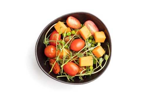 Vegetarian vegetable salad of tomatoes, pumpkin, microgreen pea sprouts isolated on white