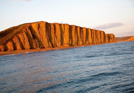 Golden afternoon light on sandstone cliffs, East Cliffs, West Bay, Bridport, Dorset, England, UK