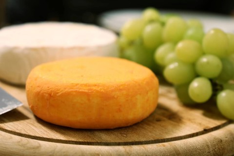 Cheese platter with various types of soft cheese and grapes