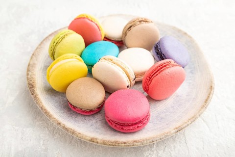 Multicolored macaroons on ceramic plate on gray concrete background. side view, still life, close