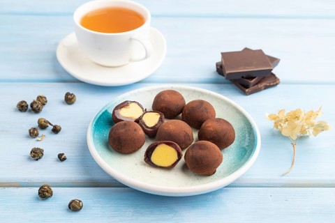 Japanese rice sweet buns chocolate mochi filled with cream and cup of green tea on blue wooden