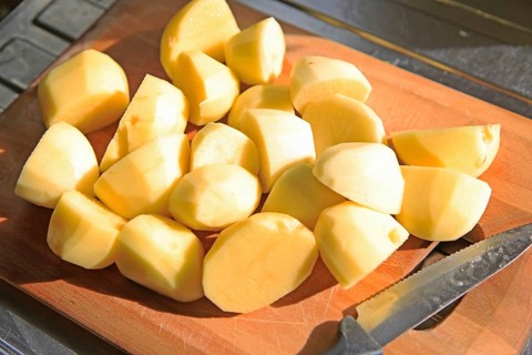 Peeled cut chopped potatoes on chopping board with kitchen knife