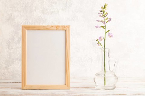 Wooden frame with hosta flowers in glass vase on gray concrete background. side view, copy space,