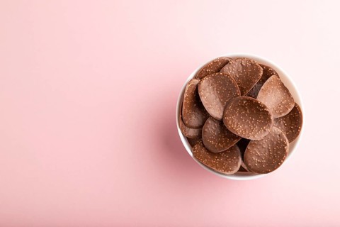 Chocolate chips with caramel on pink pastel background. top view, flat lay, copy space