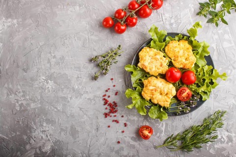 Minced chicken cutlets with lettuce, tomatoes and herbs on a gray concrete background. top view,