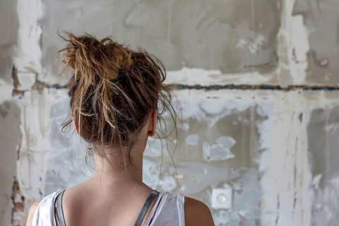 Young woman looking at old run down wall in need of renovation. Generative AI, AI generated