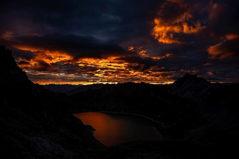 Lake Lüner See with Montafon mountains and dramatic cloudy sky at sunrise, Tschagguns, Rätikon,