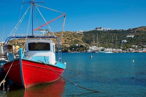 Fishing boat in a quiet harbour, surrounded by blue sea, coast and a clear sky, Skala, Patmos,