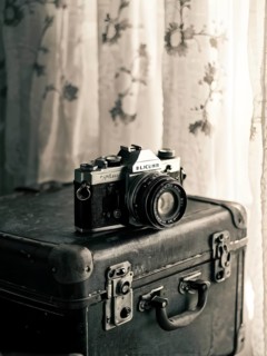 Vintage film camera surrounded by black and white photos in soft sunlight, AI generated