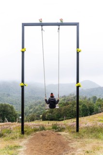Young woman sits on a swing, Cerro Pico de Novio, Chiloe, Chile, South America