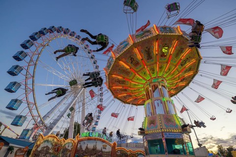 A funfair at dusk with illuminated chain carousel and Ferris wheel, Europa Rad, rides, wave flight,
