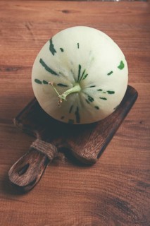 Dino melon, white with green stripes, small size, on the table, close-up, no people