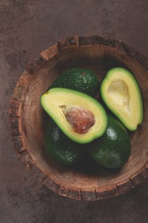Fresh, sliced avocado, in a wooden plate, top view, food background, concept, food styling