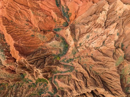 Eroded mountain landscape, top-down, canyon with red and orange rock formations, aerial view,