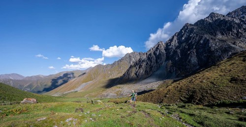 Mountaineers on a hiking trail, green high valley, Keldike Valley on the way to the Ala Kul Pass,