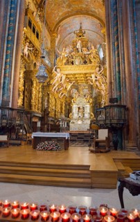 Baroque church interior with golden decorations, altar and burning candles in the foreground,