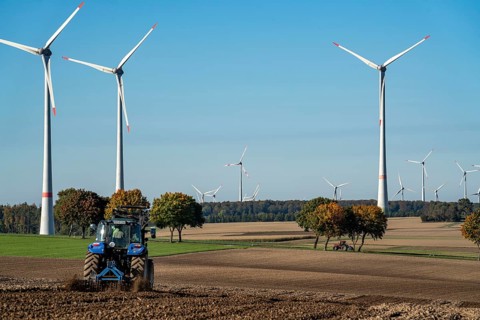 Farmer working in the fields, with a tractor, wind farm above the village of Lichtenau,