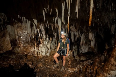 Young woman with helmet and headlamp, tourist between stalactites and stalagmites in a stalactite