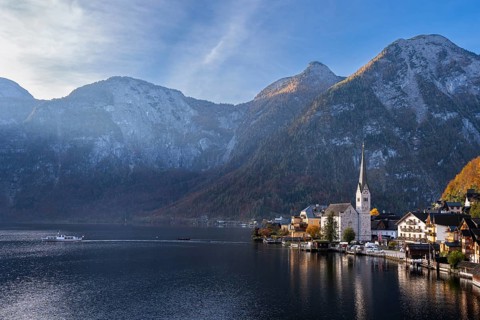 View of Hallstatt and Lake Hallstatt as well as the surrounding mountains. A boat on the lake. In