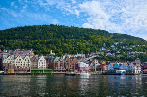 Picturesque coastal town with colourful houses and densely wooded hills in the background, boats on
