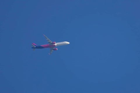 Airbus aircraft of Wizz air airlines flying across a blue sky, England, United Kingdom, Europe