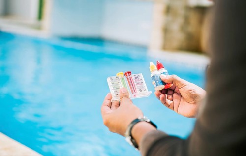 Person testing the PH of the swimming pool. Hand holding tester kit to measure chlorine and ph in