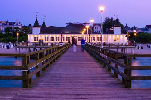 Illuminated pier with strolling people and buildings in the evening light, calm evening mood on the